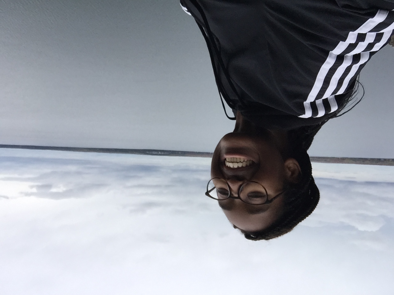 girl smiling on a cliff outside with the view of water